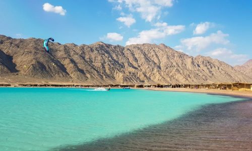 Kite surfing in Dahab , with mountains in background and clear beach water in sunny day , Blue lagoon , abo ghaloom , three pools
